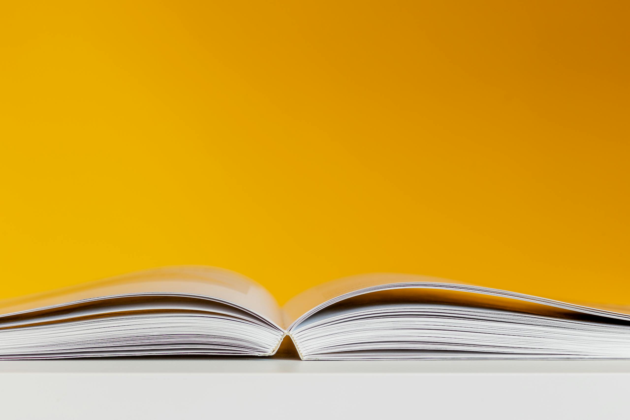 A close-up shot of an open book with a vivid yellow background, perfect for creative and conceptual design.